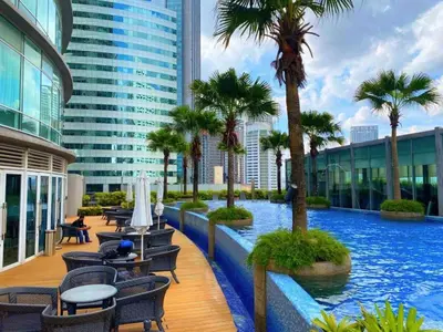 a pool in a building with palm trees and chairs at Garden City of Lights Vortex Suites in Kuala Lumpur