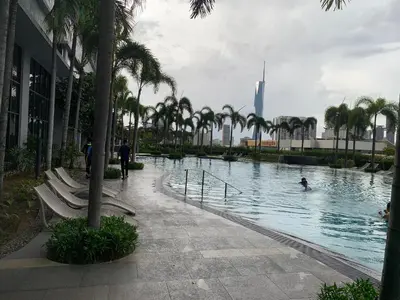 a pool with palm trees and people swimming in it at Homestay at Trion Kuala Lumpur in Kuala Lumpur