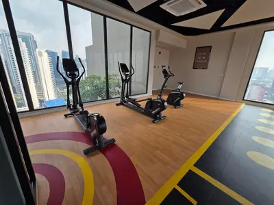 a gym with cardio machines in a room with windows at KLCC View Pool & Gym 1 Bedroom Near LRT and Mall in Kuala Lumpur
