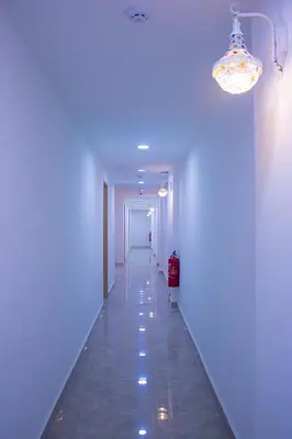 a long hallway with a white wall and a chandelier at Astarr Hotel BB in Kuala Lumpur