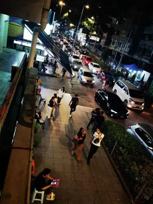 a group of people walking on a sidewalk at night at Day Cocoon In City Kuala lumpur in Kuala Lumpur