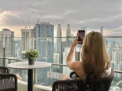 a woman taking a picture of a city skyline at 2min walk to TRX,KLCC view Gaming 2pax swimming pool in Kuala Lumpur