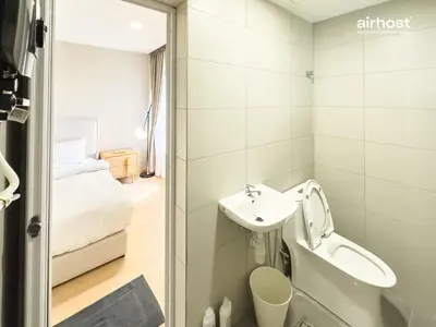 a bathroom with a sink and a toilet and a bed at Villa Putra Condo PWTC by Airhost in Kuala Lumpur