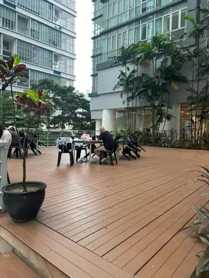 a man sitting at a table on a wooden deck at KLCC Marc Residence by Sadz in Kuala Lumpur