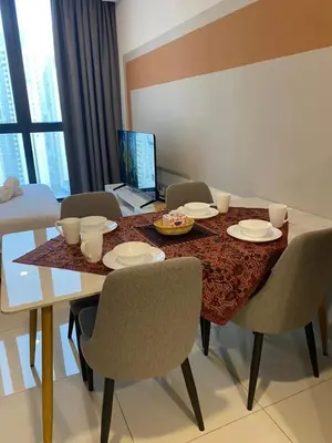 a dining room table with chairs and a laptop at Kampung Marsa at Majestic Residence, Kuala Lumpur in Kuala Lumpur