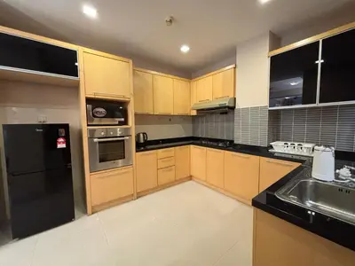 a kitchen with wooden cabinets and a black refrigerator at 183 Ampang KLCC by Widebed in Kuala Lumpur