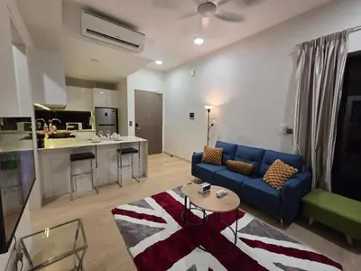 a living room with a blue couch and a kitchen at KL Star Residance KLCC by Nexus 111 in Kuala Lumpur