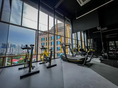 a gym with cardio equipment in a building with windows at Opus Residences KL by PILLOWTALKS in Kuala Lumpur