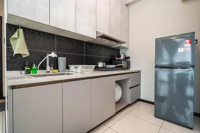a kitchen with white cabinets and a stainless steel refrigerator at Opus Residences KL by PILLOWTALKS in Kuala Lumpur
