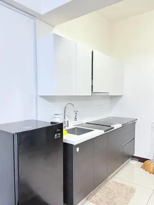 a kitchen with white cabinets and a black refrigerator at Sea Homestay in Kuala Lumpur