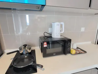 a kitchen counter with a microwave and a sink at Isola KLCC Residence in Kuala Lumpur