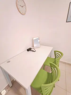 a white table with green chairs and a clock at Vivo Soho - 2 Bedrooms, Mid Valley, Bangsar South, Campus Rangers in Kuala Lumpur