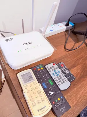 a table with three remote controls and a laptop at EST Establishment Bangsar in Kuala Lumpur