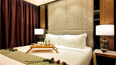 a bedroom with a bed and a table with flowers on it at Imperial Residence KLCC - MJ Home in Kuala Lumpur