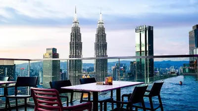 a table and chairs on a balcony with the petronas towers at Imperial Residence KLCC - MJ Home in Kuala Lumpur