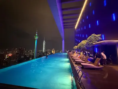 a swimming pool on the roof of a building at night at Platinum Klcc by StayAura in Kuala Lumpur