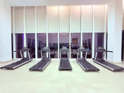 a row of treadmills in a gym with windows at Platinum Klcc by StayAura in Kuala Lumpur