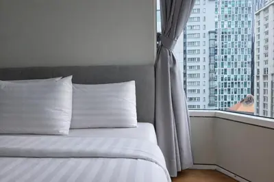 a bed with white pillows in front of a window at Sky Suites KLCC By Sky Management in Kuala Lumpur