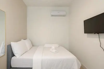 a small room with a bed and a flat screen tv at Majestic KLCC By Flora in Kuala Lumpur
