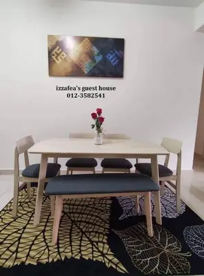 a table with two chairs and a vase of flowers on it at Izzafea in Ampang