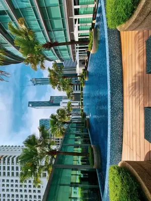 a swimming pool with palm trees on the side of a building at Vortex suites klcc by ARICA in Kuala Lumpur