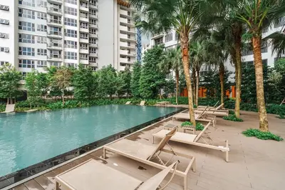 a swimming pool with chaise lounge chairs and palm trees at Deluxe 2BR Agile Bukit Bintang by RumaBnB in Kuala Lumpur