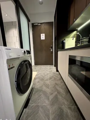 a washing machine in a kitchen with a door at KLCC View Suites By Scarletz in Kuala Lumpur