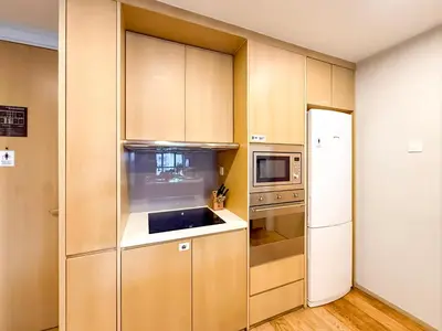 a kitchen with wooden cabinets and a refrigerator at KLCC Spacious Top Floor, Grand, Slides and Big Bathtub Kula Lumpur in Kuala Lumpur