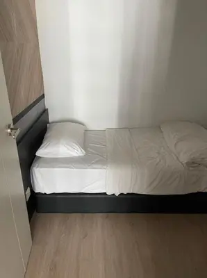 a small bed in a small room with white sheets at Arte Plus Homestay Condo in Kuala Lumpur