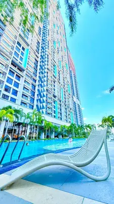 a white bench in front of a pool with tall buildings at Trion KL Family Residences in Kuala Lumpur