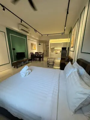 a bedroom with a large white bed and a living room at Chamber Residence klcc by Cozy Dream in Kuala Lumpur
