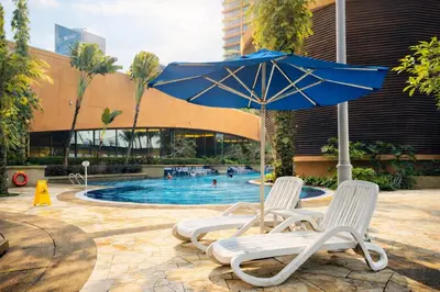 two chairs and an umbrella next to a swimming pool at Signature Stay Times Square, Kuala Lumpur in Kuala Lumpur