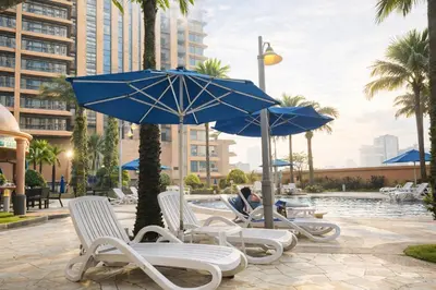a group of chairs and umbrellas next to a pool at Signature Stay Times Square, Kuala Lumpur in Kuala Lumpur