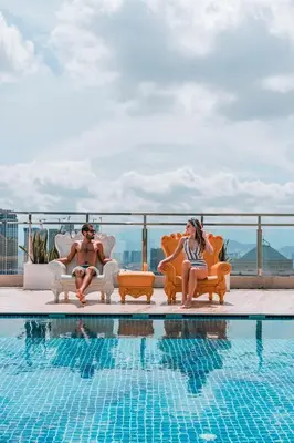 a man and woman sitting next to a swimming pool at Dorsett Hartamas with Rooftop Pool and Bathtub in KL City #215 in Kuala Lumpur