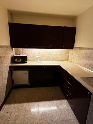 a kitchen with black cabinets and a microwave on a counter at Texas Service Suites At BTS Kuala Lumpur in Kuala Lumpur
