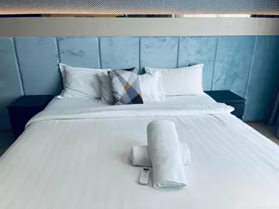 a large white bed with a remote control on it at Aurora Suites At Star Residences in Kuala Lumpur