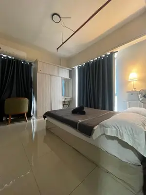 a bedroom with a bed and a chair and windows at Nour Homestay KLCC View - COMFORT in Kuala Lumpur