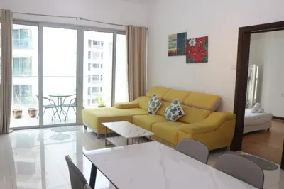 a living room with a yellow couch and a table at Regalia SkyPool8 in Kuala Lumpur