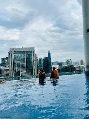 a man and woman sitting in a infinity pool on a building at LUXE KLCC SKY LiNE in Kuala Lumpur
