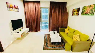 a living room with a green couch and a tv at RegaliaA Residences in Kuala Lumpur
