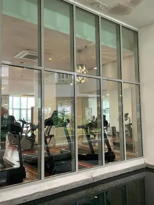 a gym with mirrored windows and people exercising on tread machines at RegaliaA Residences in Kuala Lumpur