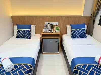 two beds in a small room with a table between them at Astarr Hotel KL in Kuala Lumpur