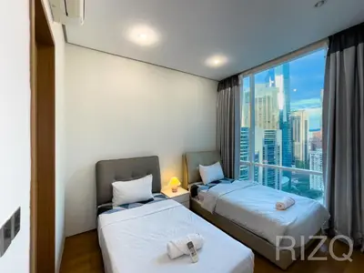 two beds in a room with a large window at SOHO SUITES KLCC BY Homestay in Kuala Lumpur