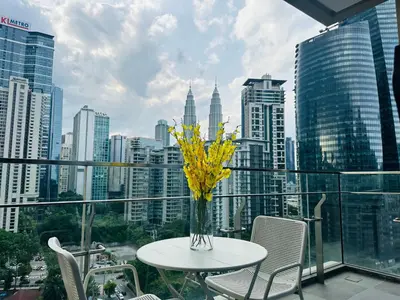 a table with a vase of yellow flowers on a balcony at KLCC City View luxury Suites in Kuala Lumpur