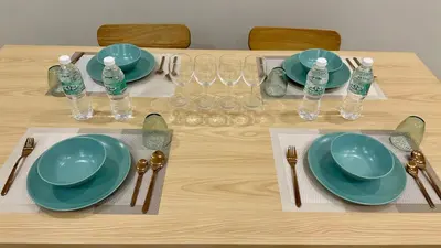 a wooden table with plates and glasses and water bottles at KLCC City View luxury Suites in Kuala Lumpur
