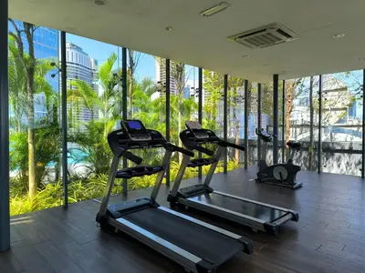 a gym with cardio equipment in a building with windows at The Dorsett Bukit Bintang KL in Kuala Lumpur