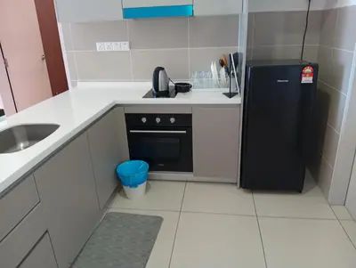 a small kitchen with a black refrigerator and a sink at Family Suites at TRION KL in Kuala Lumpur