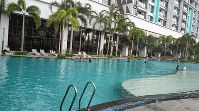a swimming pool in front of a building with palm trees at Family Suites at TRION KL in Kuala Lumpur