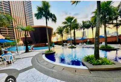 a large swimming pool with palm trees in a city at Time square midnight suites KL in Kuala Lumpur