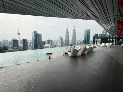 a man sitting in white chairs on the edge of a building at KLCC VIEW RESIDENC, I M P E R I A L , By LUXORA in Kuala Lumpur